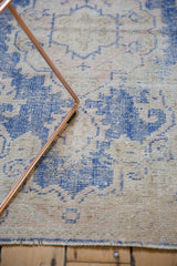 Distressed vintage Oushak runner with cobalt blue and ivory scrolling design, foundation visible.