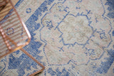 Distressed Oushak runner's curvilinear Rococo pattern, showing soft cobalt blue and antique ivory hues.