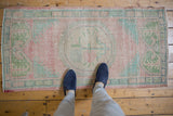 Vintage distressed Oushak rug runner; faded pink, seafoam, ivory, blush, and green floral medallion.