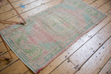 Distressed Oushak rug pile with even wear, faded pink, seafoam, and ivory border.