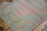 Distressed vintage Oushak rug texture, with faded pink, green, ivory, and foundation visible.
