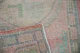Distressed vintage Oushak rug pile showing worn knots, exposed foundation, and secured edge.