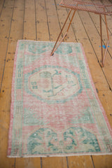 Distressed pile and border of a vintage Oushak rug in faded pink and seafoam green.
