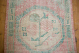 Distressed Oushak runner pile with soft pink, ivory, and teal floral motif.