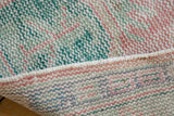 Distressed pink and green Oushak rug pile with visible knot heads and hand-knotted foundation.