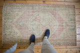 Vintage Distressed Oushak rug with faded dusty rose, beige, and forest green, showing foundation.