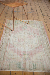 Distressed Oushak rug's worn hexagonal medallion with faded dusty rose and green floral patterns.