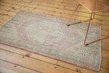 Vintage distressed Oushak rug corner with faded rose and green laurel leaf border.