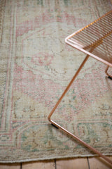 Distressed Oushak rug texture, faded dusty rose and green pattern with foundation showing through.