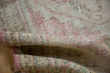 Close-up of distressed Oushak rug's faded rose edge and worn low pile.