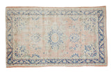 Pale dusty rose distressed vintage Oushak rug with cobalt blue medallion and floral design.