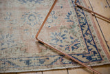 Distressed vintage Oushak rug texture with faded rose, blue, ivory patterns, secured end.