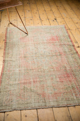 Textural detail of a distressed Oushak rug with faded blush, pink, and seafoam green.