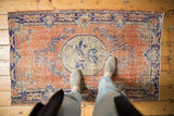 Distressed vintage Oushak rug showing even wear with dusty rust, cobalt blue medallion, and vinery details.