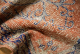 Textured close-up of a distressed vintage Oushak rug in dusty rust, cobalt blue, and ivory.