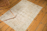 Distressed Oushak rug corner showing low pile texture, beige, sand, and ivory tones.