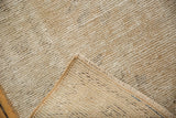 Folded corner of a vintage distressed Oushak rug revealing beige pile and hand-knotted foundation.