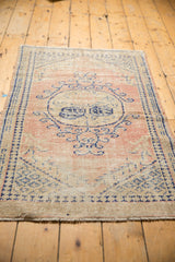 Distressed vintage Oushak rug corner with faded dusty blush and denim blue vinery.