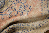 Distressed vintage Oushak rug's textured pile in dusty blush, beige, and faded blue.