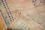 Distressed Oushak rug corner revealing hand-knotted foundation and soft blush pile.