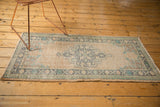 Distressed beige field and scalloped dusty charcoal medallion on a vintage Oushak rug corner.