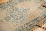 Evenly worn texture of a distressed Oushak rug, with beige, dusty charcoal, and teal.
