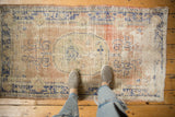 Distressed Oushak rug with faded dusty blush, cobalt blue medallion, and feet.