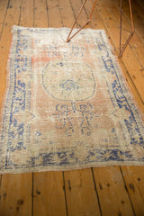 Distressed dusty blush and faded blue floral motifs on a vintage Oushak rug.