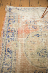 Low pile texture of a distressed vintage Oushak rug with faded blush, blue, and visible foundation.