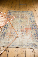 Distressed vintage Oushak rug in faded dusty blush and cobalt blue, showing wear to foundation.
