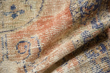 Distressed Oushak rug pile revealing knot heads and faint foundation in blush and denim blue.