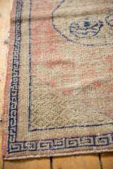 Distressed Oushak rug corner with cobalt blue Greek key border and antique ivory, pink field.