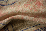 Distressed Oushak rug pile texture showing blush, beige, and cobalt blue knot heads.