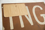 Back of vintage painting, featuring handwritten note and white letters.