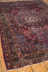 Vintage Persian Meshed rug showing intricate rose and dark blue borders with overcast fringe.