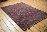 Corner of the vintage Meshed rug, showing deep red and blue florals with overcast end.
