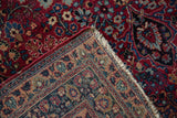 Folded vintage Meshed rug corner: cherry red floral pattern, soft wool, woven foundation.