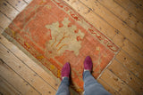 Antique Oushak fragment rug with oversized pale gold floral design, peach field, and low pile texture.