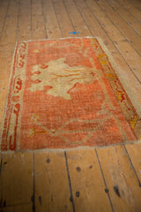 Secured side of antique Oushak rug fragment, showing low pile and peach vine border.