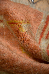 Low pile texture and knot heads of the antique Oushak rug in peach, yellow, red.