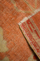 Antique Oushak rug's hand-knotted foundation and low peach pile with faded floral design.
