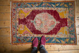 Overhead view showing the scale of an antique Anatolian rug with a worn cherry red field and teal floral border.