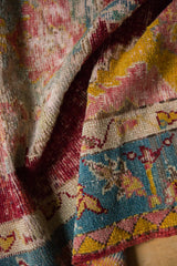 Hand-knotted texture and original polychrome selvage of a draped antique Anatolian rug.
