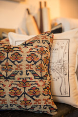 Close-up of a vintage Kurdish pillow, showing distressed floral pattern in blue, orange, red.