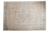 Distressed Oushak carpet with pale dusty blush medallion and faded blue floral patterns on antique ivory.