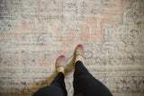 Feet on distressed Oushak carpet, pale blush, antique ivory, denim blue tones.