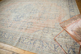 Distressed vintage Oushak carpet texture showing blush, ivory, and denim blue motifs.