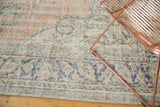 Distressed Oushak rug showing worn texture, pale dusty blush, ivory, denim blue floral motifs.