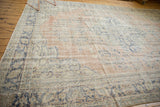 Distressed Oushak rug with blush and ivory field, blue floral motifs, and visible foundation.