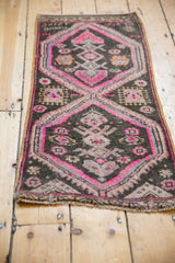 Distressed Oushak rug detail showing vibrant bubble gum pink geometric pattern on charcoal.